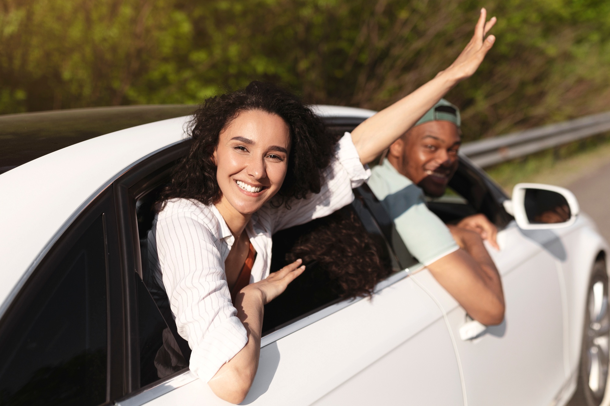 Multiracial best friends traveling together by car, looking through windows, having fun journey in